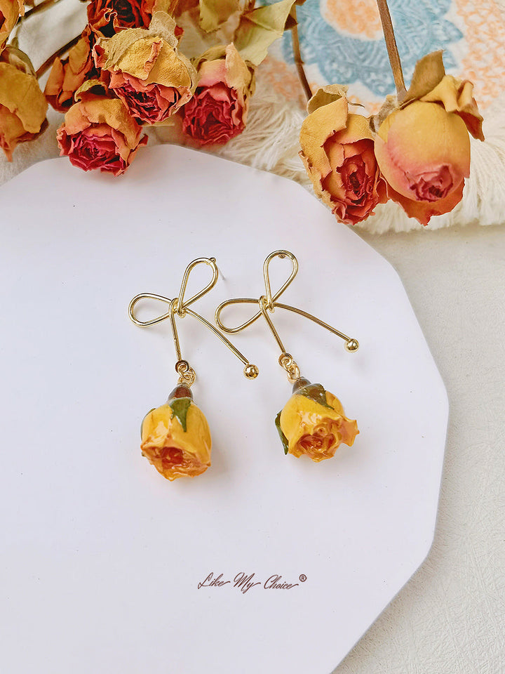Orecchini con fiori secchi e fiocco di rosa